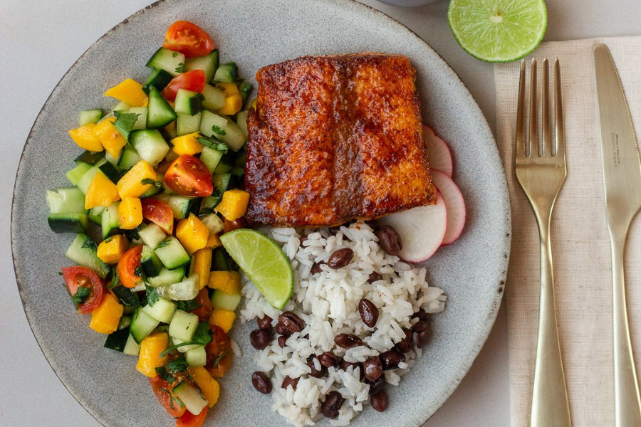 Fish taco bowl with chopped veggies on the side, rice with beans, and salmon.