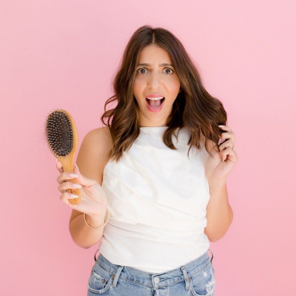 Tallene with a hair brush holding her hair and screaming in frustration over PCOS hair loss