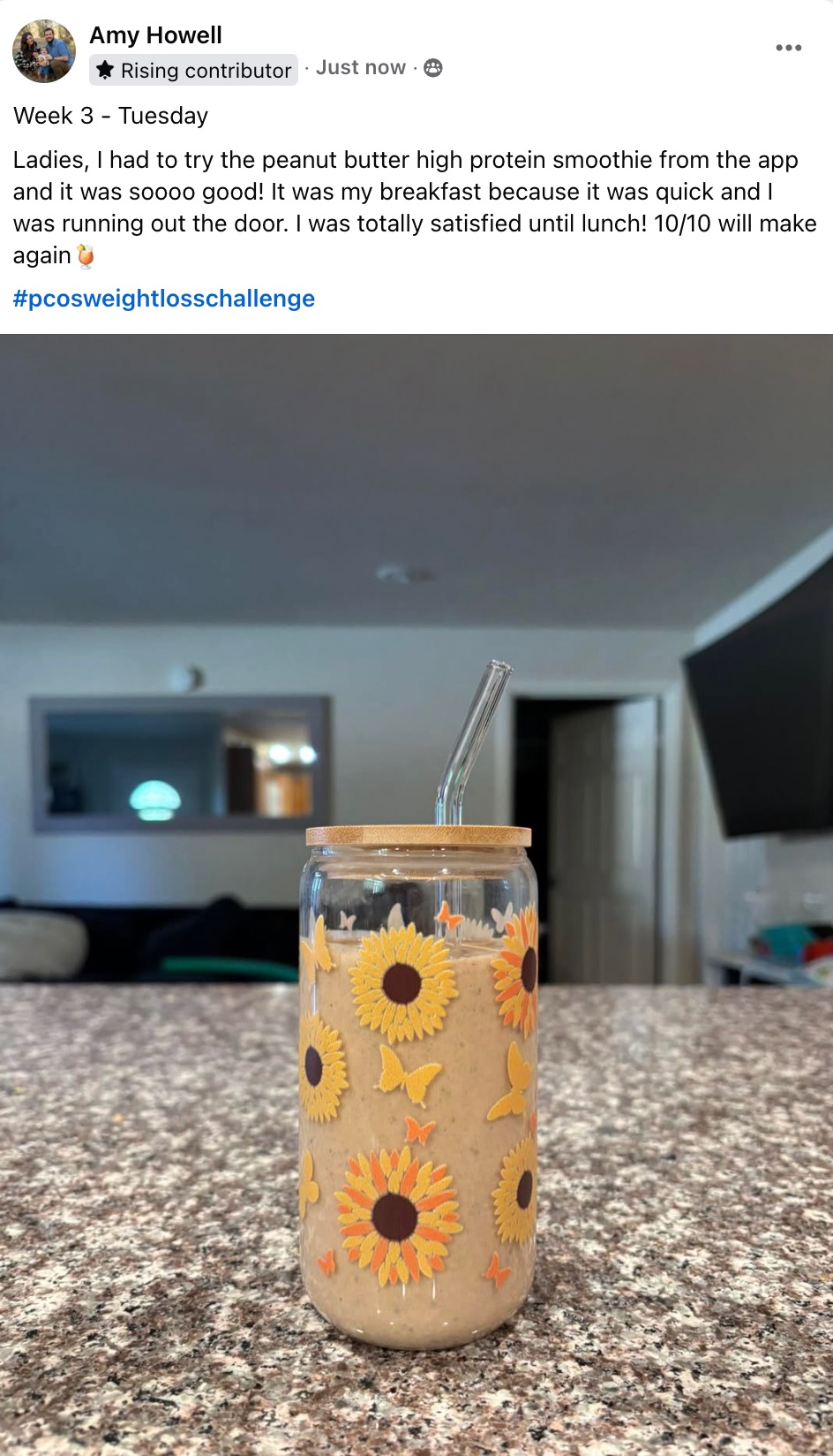 Peanut butter protein smoothie in a sunflower-decorated mason jar on a speckled countertop.